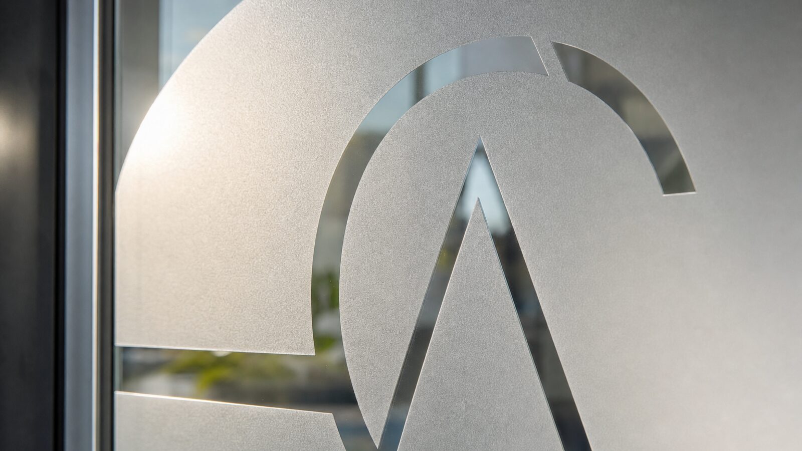 Close-up of a custom cut-to-pattern frosting logo on a glass entry door