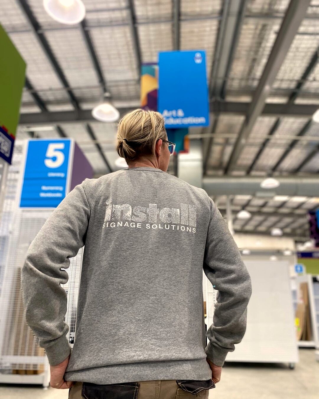 Claire in an 'install' branded hoodie working on a commercial signage site