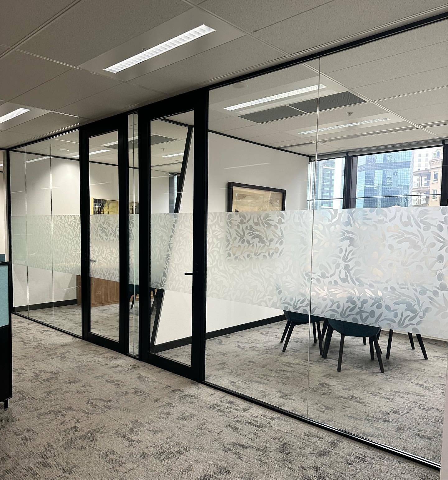 Frosted privacy film on full-height office glass partitions in a reception