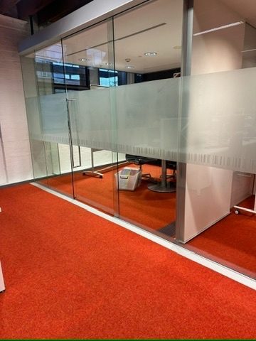 Custom frosted glass partitions in a meeting room with red carpet
