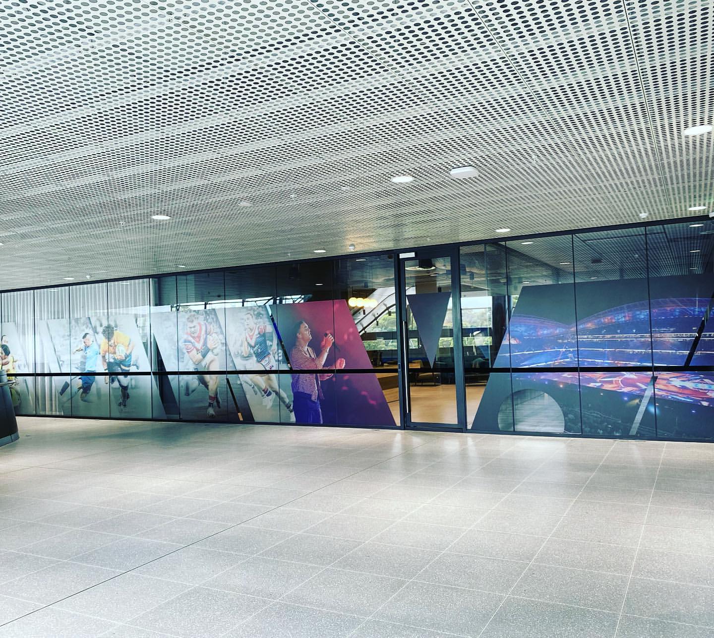 Workers installing tinting film on a large glass skylight