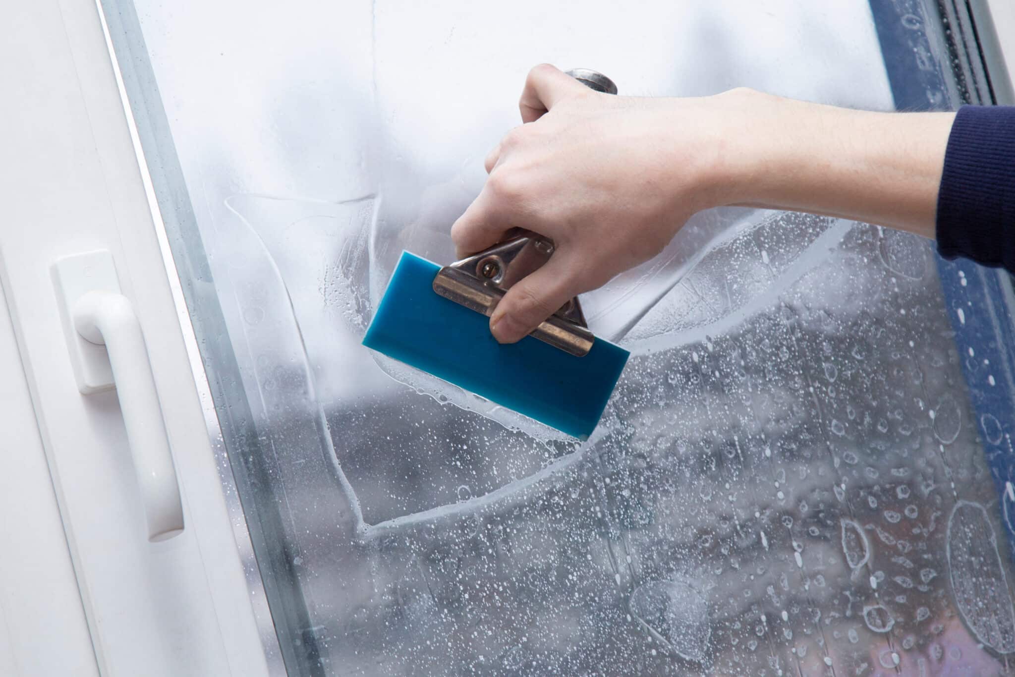 Squeegee smoothing solar tint film against a residential window