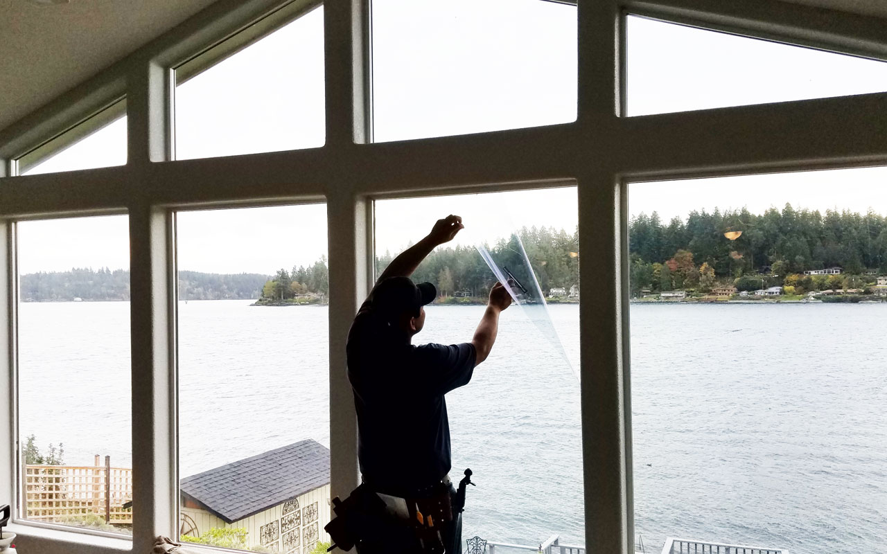Installer trimming solar window film on a lakeside home