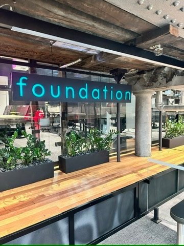 Backlit 'foundation' neon-style wordmark above a bar bench