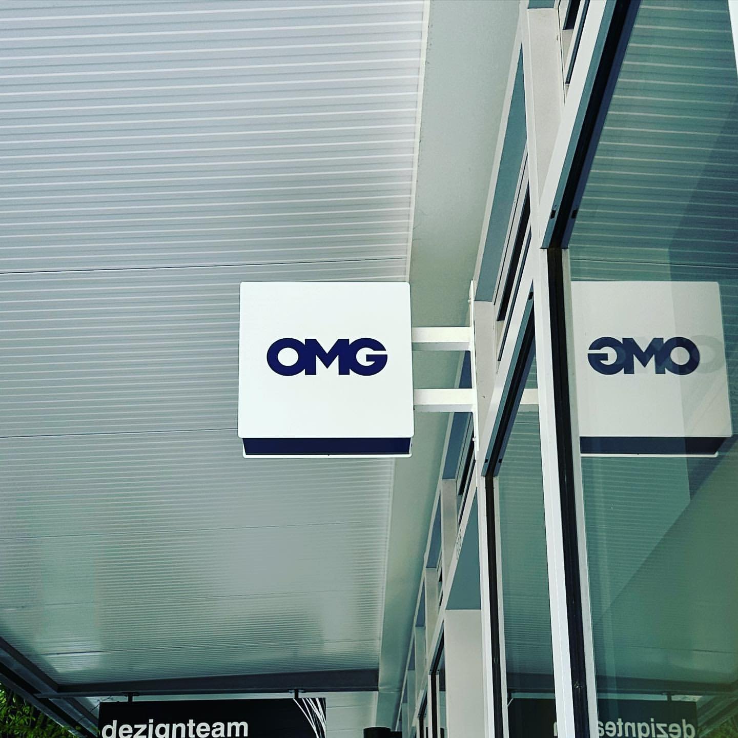 OMG illuminated blade sign against dark exterior facade