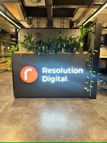 Backlit Resolution Digital reception logo on dark panel with planters