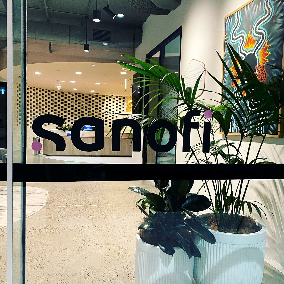 Sanofi logo on frosted glass reception with planted backdrop