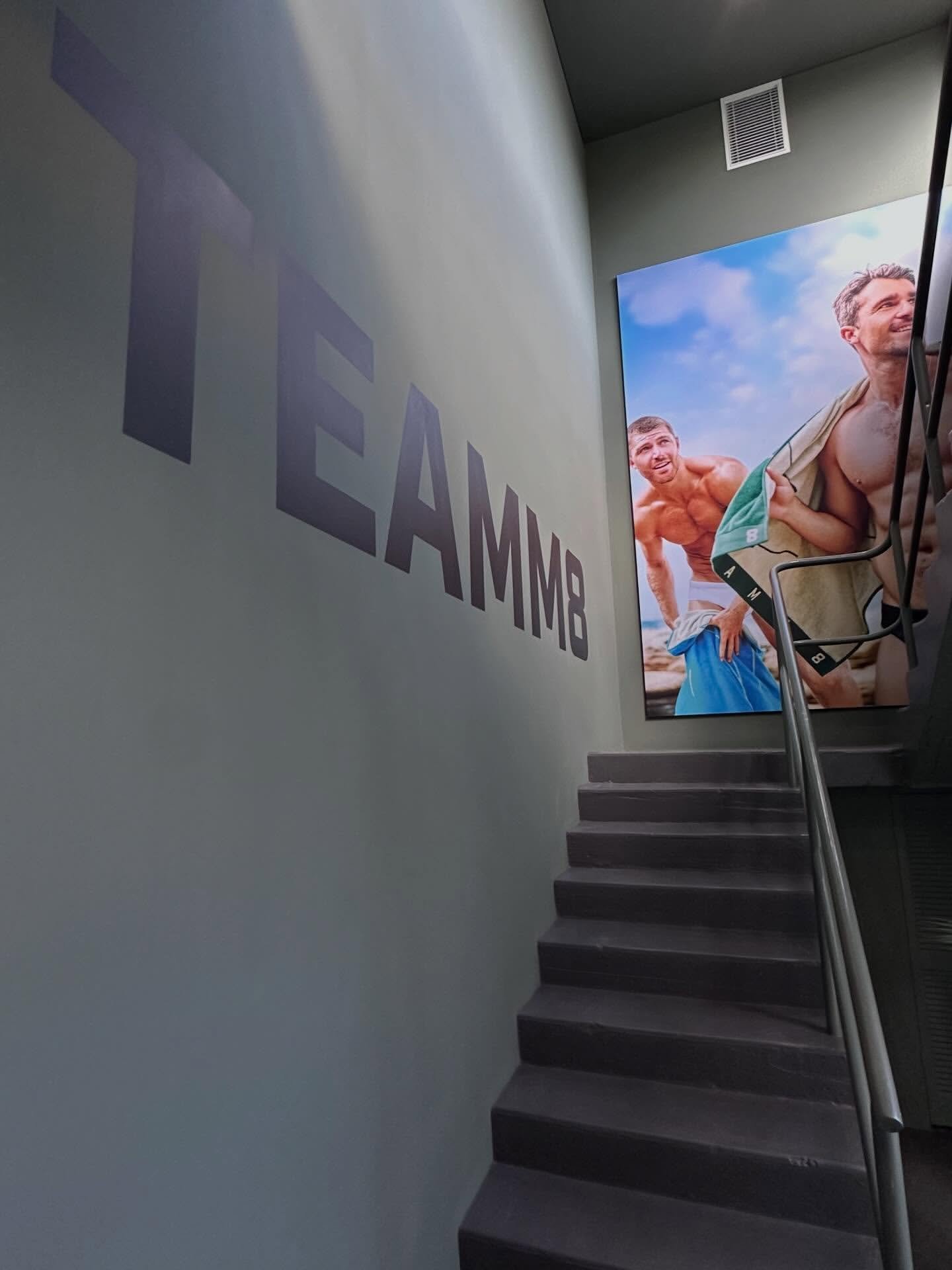 TEAMM8 stairwell dark wordmark with beach photograph panel